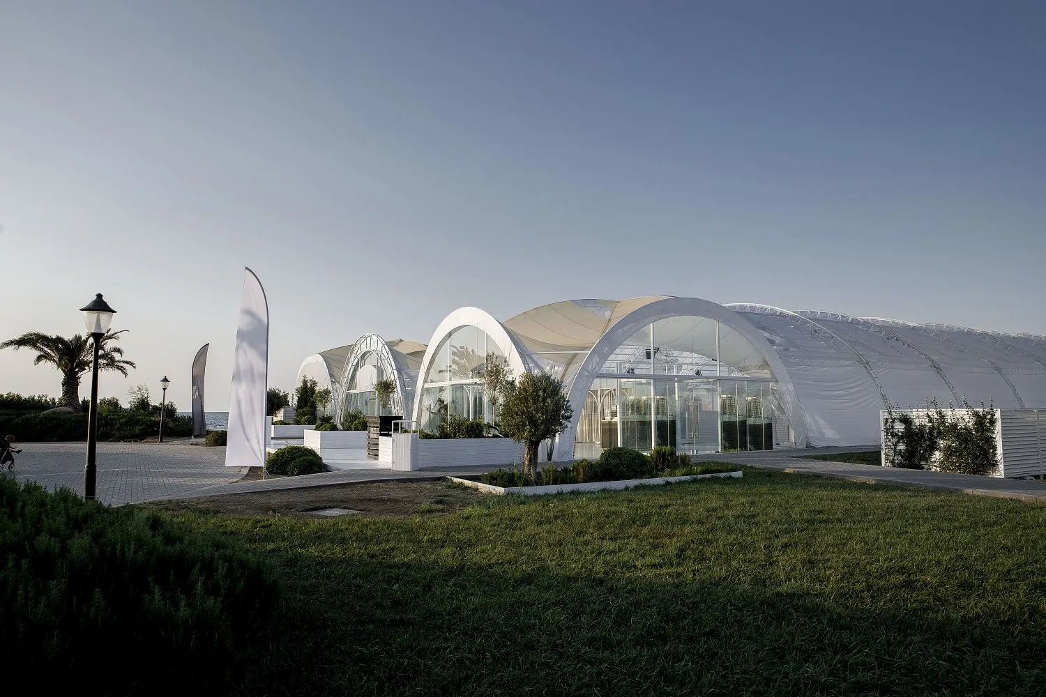 Шатёр Event Hall вечером: арки из белой мембраны и прозрачные стены